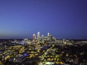 A twilight aerial view of the lit Charlotte skyline.